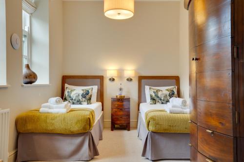 a bedroom with two beds and a dresser at Spence Lodge: Beautiful 2-Bedroom Stone Cottage in Alnmouth