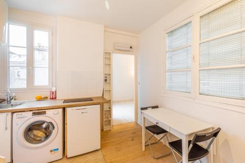 une cuisine avec une machine à laver et une table dans l'établissement GuestReady - Joli studio cosy dans le 17ème Arr., à Paris