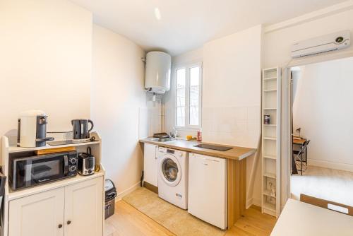une cuisine avec un lave-linge et un micro-ondes dans l'établissement GuestReady - Joli studio cosy dans le 17ème Arr., à Paris