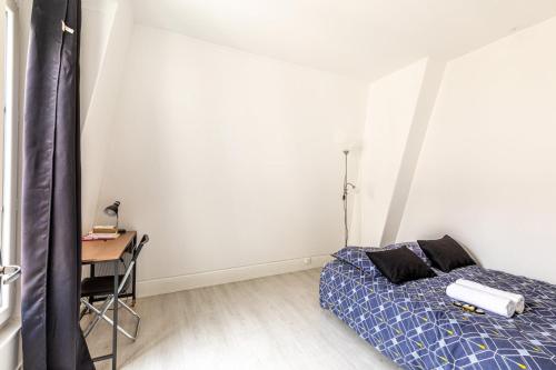 une chambre avec un lit, une table et un bureau dans l'établissement GuestReady - Joli studio cosy dans le 17ème Arr., à Paris