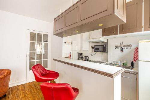 - une cuisine avec 2 chaises rouges et un comptoir dans l'établissement GuestReady -Superbe Appartement dans le 14ème Arr., à Paris