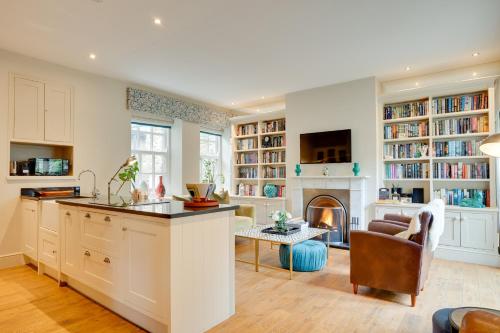 a kitchen with a living room with a fireplace at Spence Lodge: Beautiful 2-Bedroom Stone Cottage in Alnmouth