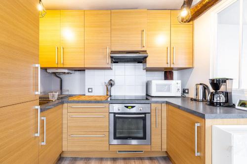 une cuisine avec des armoires en bois et un four à plaques de cuisson dans l'établissement GuestReady - Appartement Cosy au Cœur de Paris, à Paris