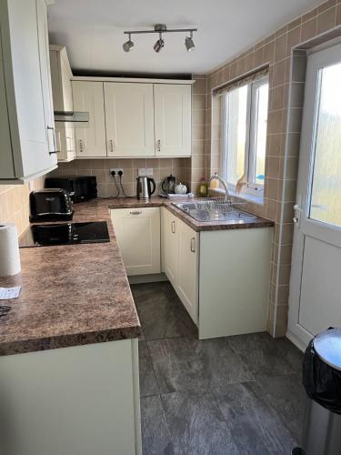 a kitchen with white cabinets and granite counter tops at A Family Cottage in Tenby in Tenby