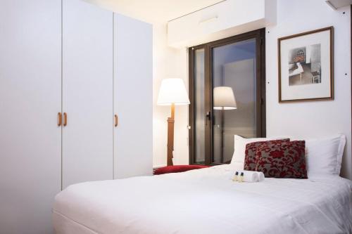 une chambre avec un lit blanc avec un oreiller rouge dans l'établissement GuestReady - Studio lumineux à Folie-Méricourt, à Paris