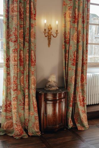 a room with curtains and a cross on a table at Hôtel l'Abbaye in Saint-Cyprien