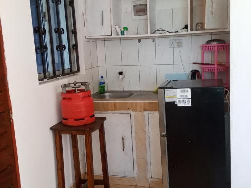 a kitchen with a black refrigerator and a sink at Schneider in Mtwapa