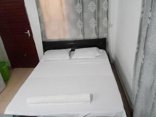 a bed with white sheets and pillows in a room at Schneider in Mtwapa