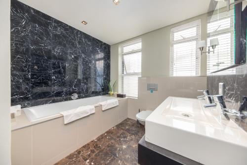 a bathroom with a sink and a tub and a toilet at O on Kloof Boutique Hotel & Spa in Cape Town
