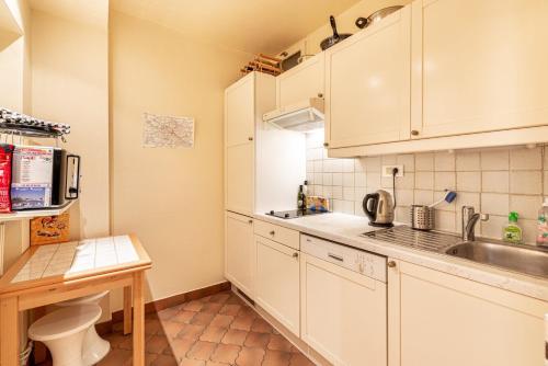 une petite cuisine avec des armoires blanches et un évier dans l'établissement GuestReady - Superb Appt près du Pathéon, à Paris