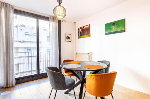 une salle à manger avec une table et des chaises et une fenêtre dans l'établissement GuestReady - Appartement baigné de lumière, à Paris