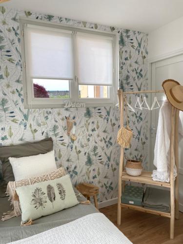 una camera da letto con carta da parati floreale, un letto e una finestra di Le Refuge du Lac a Chaumousey