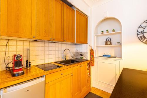 une cuisine avec des armoires en bois et un évier dans l'établissement GuestReady - Appartement Élégant dans Le Marais, à Paris