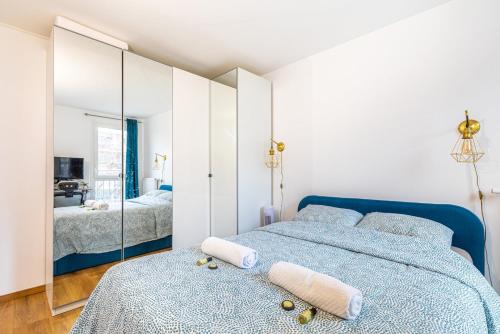 une chambre avec un lit bleu et un miroir dans l'établissement GuestReady - Chic Apt Near Passerelle Bichat, à Paris