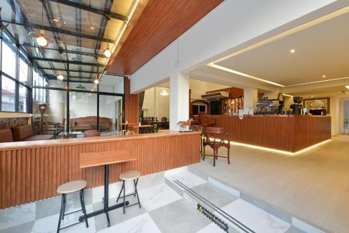 a lobby with a bar with stools and tables at Ratchathewi Hyde Away in Pratunam