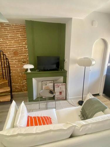 un salon avec un canapé blanc et une télévision dans l'établissement Le 23, cocon dans le centre historique, à Montauban