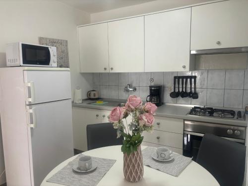 a kitchen with a table with a vase of pink roses at Apartments Manila in Zagreb