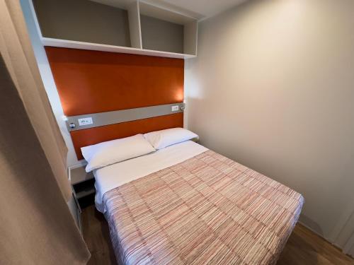 a small bedroom with a bed with a wooden headboard at Camping Serenissima in Malcontenta