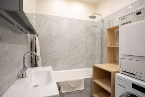 une salle de bain blanche avec un lavabo et une douche dans l'établissement Chic Flat 2 rooms Georges V, à Paris