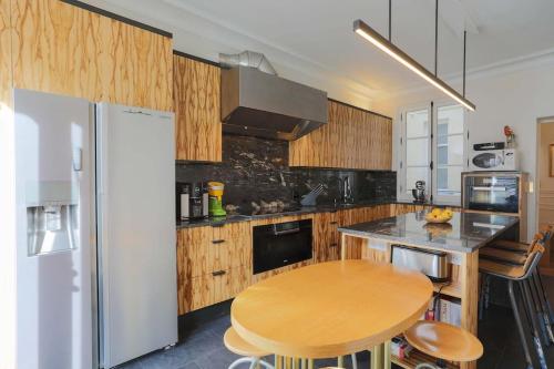 - une cuisine avec des placards en bois, une table et un réfrigérateur dans l'établissement Chic Flat 2 rooms Georges V, à Paris