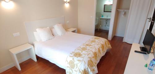 1 dormitorio con 1 cama blanca y TV en Hostal Camponaraya en Camponaraya