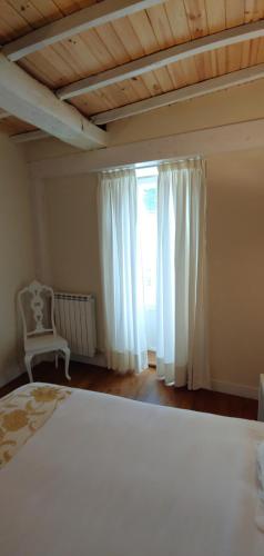 1 dormitorio con cama blanca y ventana en Hostal Camponaraya en Camponaraya