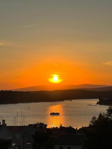 a sunset over a body of water with a boat at Panorama Penthouse Punat in Punat