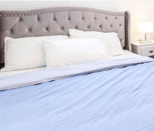 1 cama con sábanas azules y almohadas blancas en New Luxury Suite 6Mins To Falls, Free Parking, en Niagara Falls