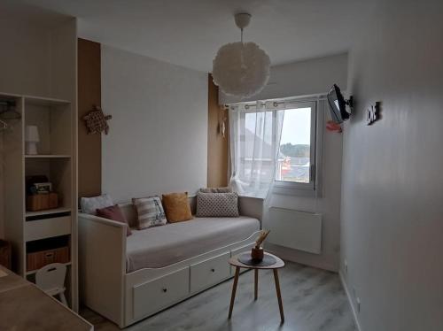 Cette petite chambre comprend un canapé et une fenêtre. dans l'établissement Un petit nid douillet en front mer et vue St Jean, à Saint-Jean-de-Monts