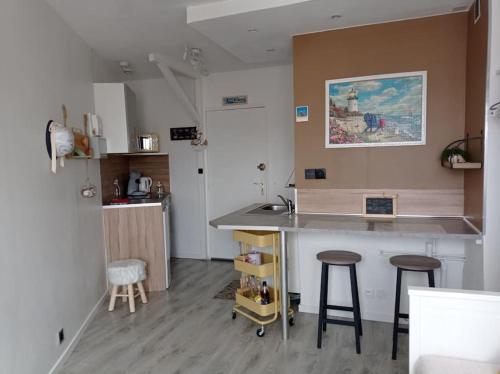 une cuisine avec deux tabourets de bar et un comptoir dans l'établissement Un petit nid douillet en front mer et vue St Jean, à Saint-Jean-de-Monts