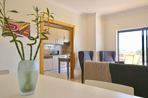 a dining room with a table and a vase with a plant at Apartamento moderno perto da marina e da praia in Lagos