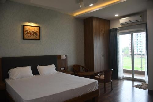 una camera con letto, tavolo e finestra di Vatika Banquet And Lawn a Gaya