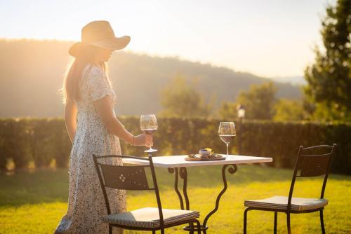 a woman standing next to a table with a glass of wine at Podere Felceto in Panzano