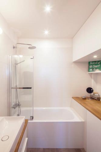 une salle de bain blanche avec une baignoire et une douche dans l'établissement GuestReady - Apt lumineux proche du Moulin Rouge, à Paris