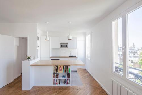 Il comprend une cuisine aux murs blancs et une grande fenêtre. dans l'établissement GuestReady - Apt lumineux proche du Moulin Rouge, à Paris