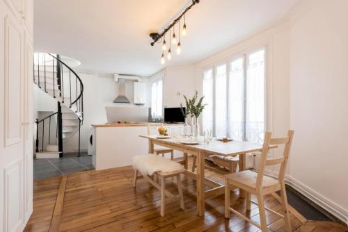 une cuisine et une salle à manger avec une table et des chaises en bois dans l'établissement GuestReady - Duplex spacieux et lumineux, à Paris