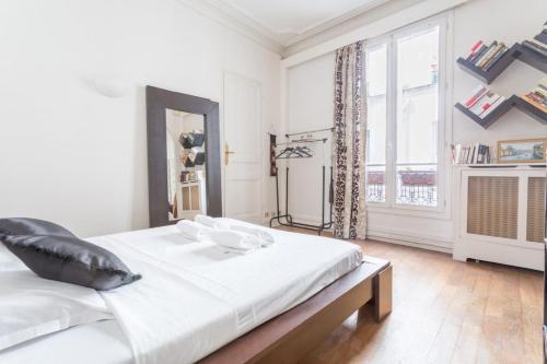 une chambre blanche avec un grand lit et une fenêtre dans l'établissement GuestReady - Très bel Appartement confortable, à Paris