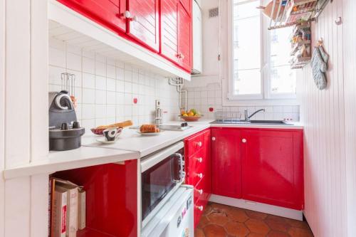 une cuisine rouge avec des murs blancs et des armoires rouges dans l'établissement GuestReady - Très bel Appartement confortable, à Paris
