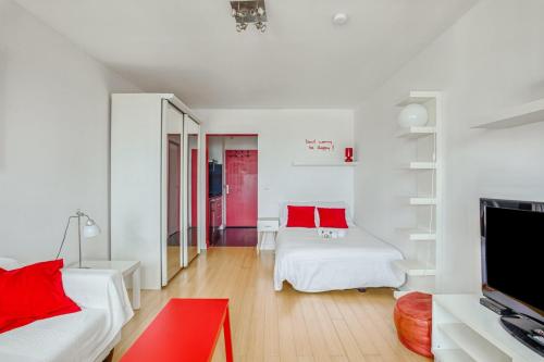 - un salon doté d'un mobilier blanc et d'oreillers rouges dans l'établissement GuestReady - Beau studio avec vue imprenable, à Paris