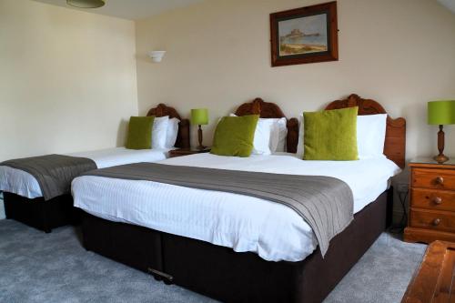 two beds in a hotel room with green pillows at The Uplands Apartments in Saint Helier Jersey