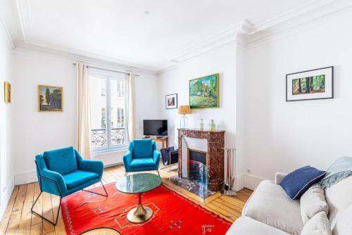 - un salon avec une cheminée et des chaises bleues dans l'établissement GuestReady - Douceur Parisienne dans le 15e arr., à Paris