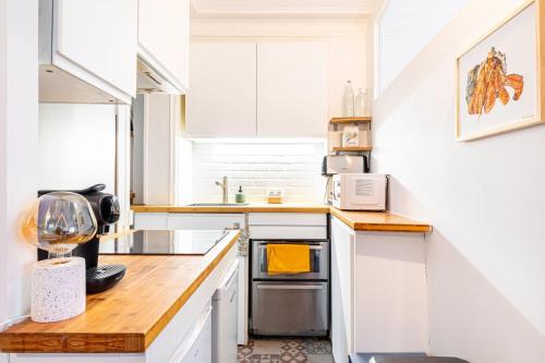 une cuisine avec des armoires blanches et un comptoir en bois dans l'établissement GuestReady - Charme et Confort dans le 11ᵉ arr., à Paris