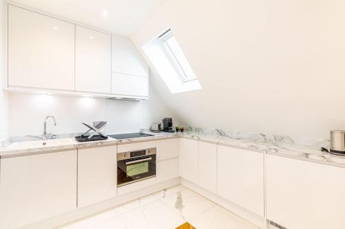 une cuisine blanche avec des armoires blanches et un évier dans l'établissement GuestReady - Appartement Grenelle, à Paris