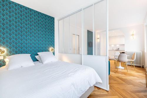 une chambre avec un lit blanc et un mur vert dans l'établissement GuestReady - Appartement Grenelle, à Paris