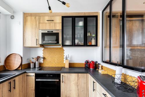 - une cuisine avec des placards en bois et des appareils noirs dans l'établissement GuestReady - Studio Chic avec Vue Panoramique, à Paris