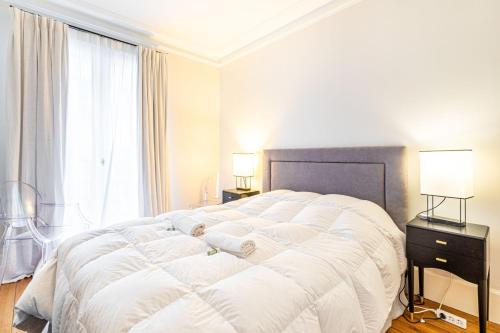 une chambre avec un grand lit blanc et une fenêtre dans l'établissement GuestReady - Séjour de charme dans le 6ème, à Paris