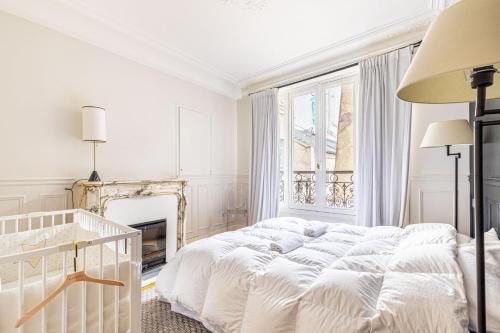 - une chambre blanche avec un lit et une cheminée dans l'établissement GuestReady - Bright stay near Jardin du Luxembourg, à Paris