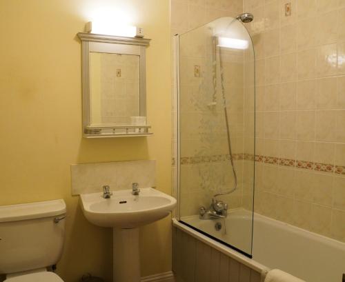 a bathroom with a sink and a toilet and a shower at The Uplands Apartments in Saint Helier Jersey