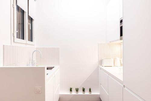a white kitchen with white cabinets and a sink at GuestReady: Designer Studio in the heart of Marais in Paris