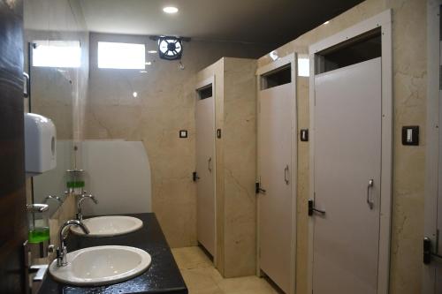 baño con 2 lavabos y 2 puertas blancas en Vatika Banquet And Lawn, en Gaya